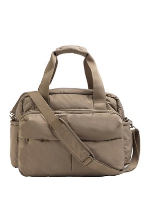 Beige pehmeä toppaus duffel-laukku, jossa on kaksinkertaiset kahvat, etupuolen vetoketjullinen tasku, sivucompartmentit ja säädettävä olkahihna pehmustuksella.