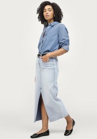 Lyseblå denim maxi nederdel med en frontslids, parret med en knap-op blå skjorte. Inkluderer et sort bælte og sorte flade sko.