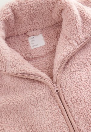 Rozā flīsa jaka ar rāvējslēdzēju priekšpusē un augstu apkakli. Audumam ir mīksts, struktūrēts apdare, un iekšpusē ir redzama kopšanas birka.