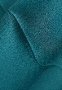 Tela de color verde azulado con una textura suave y un ligero brillo, que presenta pliegues suaves y un diseño elástico, mejorando su atractivo visual.