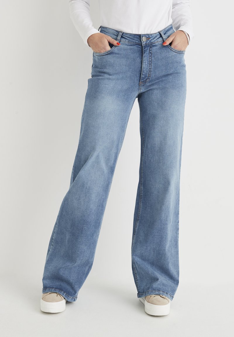 Hellblaue weit geschnittene Jeans aus Denim, mit hoher Taille, zwei Fronttaschen und einem Knopfverschluss. Strukturierter Stoff mit dezentem Verblassen.