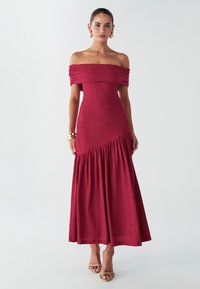 Rotes Off-Shoulder-Kleid aus strukturiertem Stoff, tailliertem Oberteil und ausgestelltem Rock. Auffällige Details sind der geraffte Ausschnitt und die Nahtakzente.