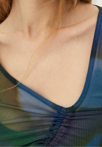 Indumento trasparente con scollatura a V profonda, dettagli arricciati su un lato e una miscela astratta di tonalità blu e verdi.