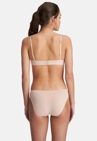 Beige BH- und Panty-Set aus glattem Material. Der BH hat verstellbare Träger und einen Hakenverschluss auf der Rückseite. Nahtloses Design für höchsten Komfort.
