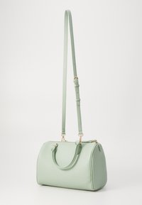 Kožená kabelka v mátově zelené barvě s zaobleným tvarem, zlatými kovovými doplňky, dvojitými rukojeti a dlouhým nastavitelným ramenním popruhem.