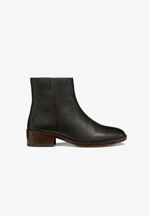 Bottine en cuir noir avec une texture lisse, bout rond et un petit talon en bois empilé. Design minimaliste et tige sans couture.