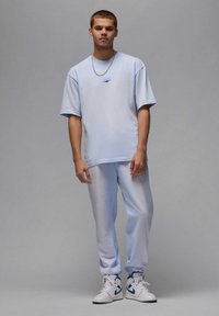T-shirt oversize azzurro chiaro e pantaloni della tuta coordinati, entrambi in tessuto morbido. Completato con un piccolo dettaglio logo e abbinato a sneakers bianche.