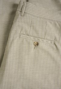 Beige randiga byxor med en texturerad väv, som har en knapp på bakfickan och välstämmda sömmar.