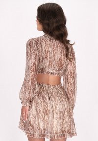 Bruine geblokte crop top met lange mouwen, elastische taille en bijpassende rok. Doorschijnende stof met een gestructureerd ontwerp en een gerimpelde zoom.