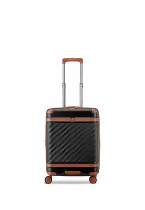 Valigia da cabina rigida nera e marrone con fronte testurizzato, manico telescopico esteso e quattro ruote girevoli su sfondo bianco.