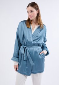 Robe kimono en satin bleu clair avec ceinture à nouer et manches amples, dotée d'un poignet texturé doux et de poches latérales.