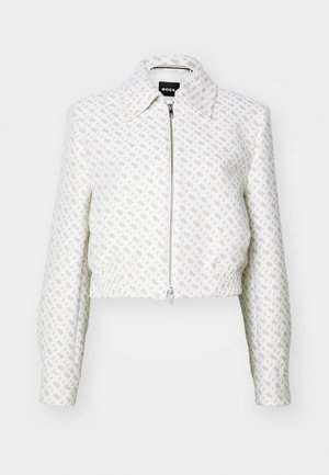 Rövidített fehér dzseki texturált mintával és elülső cipzárral. Gallérral és rugalmassá tett alsó résszel rendelkezik, ezáltal karcsú sziluettet formál.