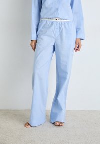 Ljusblå randig pyjamasset med knäppbar överdel och vida byxor. Tyget ser mjukt ut och har ett märkestryckt elastiskt midjeband.