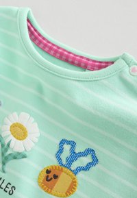 Lysegrøn babystribet skjorte med broderet hvid tusindfryd blomst og smilende bi, lyserød ginghamkant ved halsudskæringen og hjerteformet knaplukning.