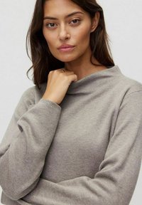 Jasnoszary sweter typu golf wyk wykonany z miękkiej dzianiny. Posiada długie rękawy oraz luźny krój z designem złożonego kołnierza.