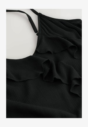 Musta mekko, jossa on kihara tekstuuri, ohut säädettävä olkaimet ja virtaava, kevyt kangas, joka laskeutuu pehmeästi.