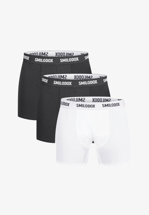 Bóxer en blanco y negro con cinturilla elástica que presenta "SMILODOX". La tela es suave; hay dos pares en negro y un par en blanco.