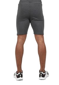 Grijze sportshorts met een strakke pasvorm, gemaakt van zacht materiaal, met een achterzak. Draagt met zwart-witte sneakers.