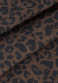 Tissu marron avec une surface texturée arborant un motif léopard noir. Le matériau semble durable avec un nervurage visible.