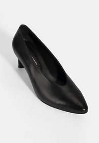 Zwarte leren pump met een spitse neus, lage hak en een gladde textuur. Beschikt over een naadloos bovenwerk en een klassieke silhouet.