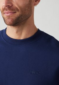 Marineblauwe sweatshirt met ronde hals, gemaakt van zachte katoen, met een gestructureerd Levi's-logo geborduurd op de borst. Soepel, klassiek ontwerp.
