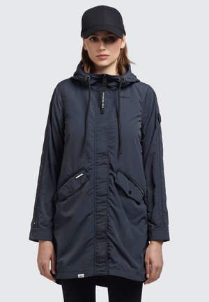 Veste à capuche navy avec fermeture éclair à l'avant, cordons élastiques, deux poches zippées et une finition douce et légère. Présente un logo sur la poitrine.