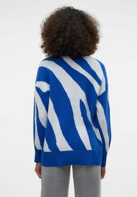 Pull à rayures bleues et blanches, coupe ample, manches longues et ourlet côtelé. Confectionné en maille douce, présentant des motifs audacieux.