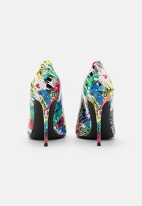 Une paire de chaussures à talons hauts colorées avec des graffitis et des motifs abstraits, présentée de l'arrière sur un fond blanc.