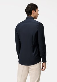 Marineblauw overhemd met lange mouwen, gemaakt van soepel stof, met een gestructureerde kraag, knoopsluiting bij de manchetten en een getailleerde pasvorm, met een subtiele glans.