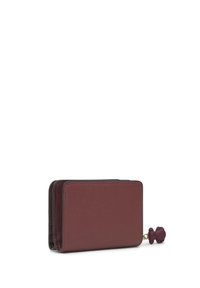 Cartera compacta de cuero texturizado rojo oscuro con cierre de cremallera y pequeño tirador en forma de oso sobre fondo blanco.