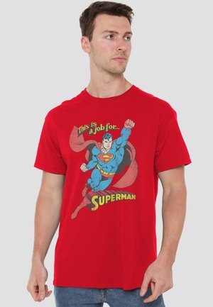 Man wearing red t-shirt with flying Superman graphic and text "This is a job for Superman" on front, looking to his right.