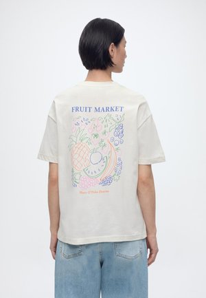 Άτομο με κοντά σκούρα μαλλιά που φοράει λευκό μπλουζάκι με πολύχρωμα σκίτσα φρούτων και το κείμενο "FRUIT MARKET" στην πλάτη, συνδυασμένο με ανοιχτόχρωμα μπλε τζιν.
