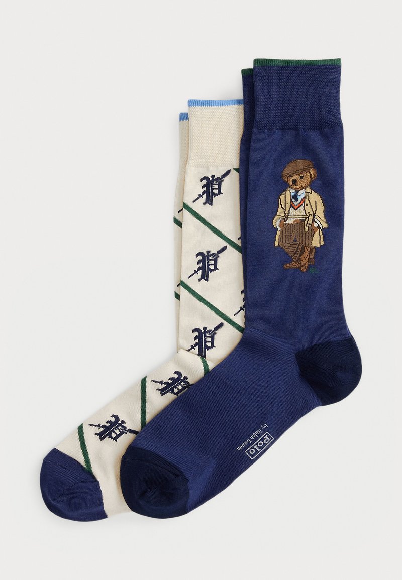 Two pairs of socks: one navy blue with a bear graphic, the other cream with green and navy diamond patterns and logo motifs.