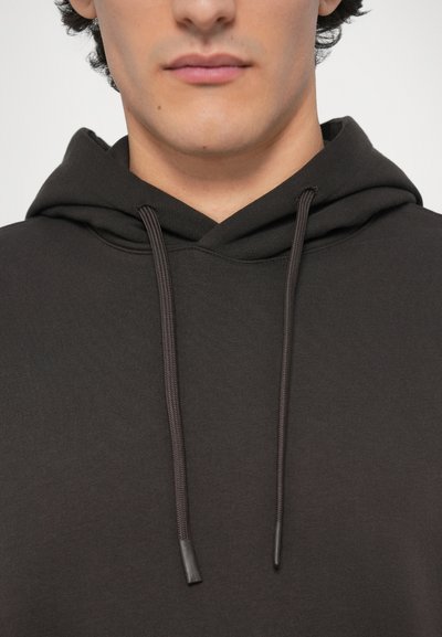 Σκούρα γκρι φούτερ με κουκούλα και κορδόνι, υφασμάτινη υφή και εμφανείς ραφές. Κοντινή άποψη του λαιμού και της κουκούλας.