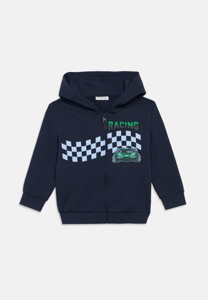 Tengerészkék cipzáras kapucnis pulóver pamut keverékből. Zöld "RACING" felirattal és grafikus autóval rendelkezik, valamint világoskék kockás mintával az elején.