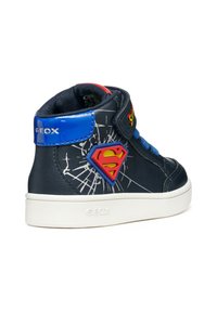 Le sneaker alte blu scuro presentano un emblematico logo di Superman dai colori vivaci, cuciture a contrasto e una suola bianca, mostrando elementi di design giocosi.