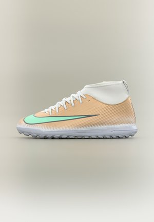 Zapatilla deportiva de caña alta beige y blanca con cordones blancos y un gran logo en forma de swoosh de color verde claro en el lateral, mostrada sobre un fondo neutro.