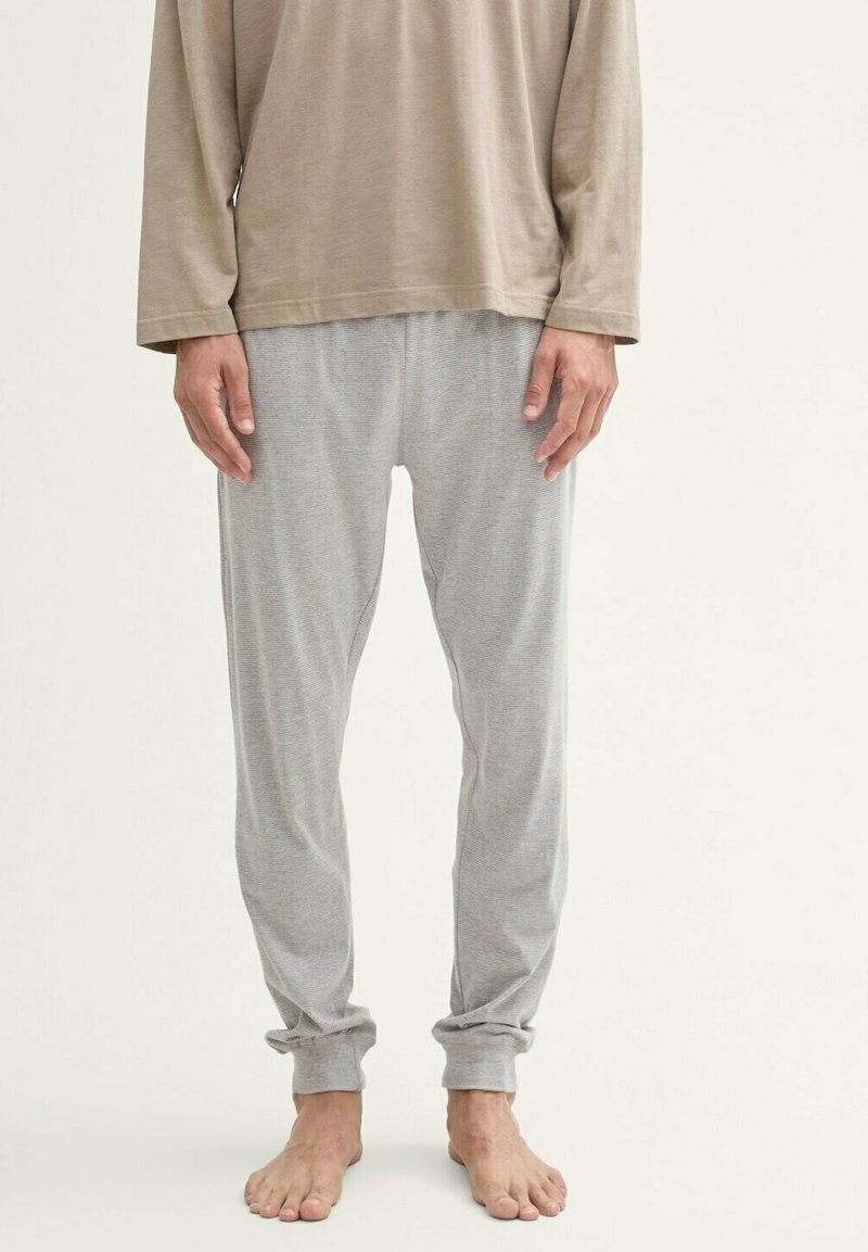 Lichtbruine long-sleeve shirt gedragen met grijs gestreepte pyjamabroek, met een ontspannen pasvorm en omgeslagen pijpen, blote voeten.