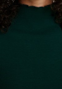 Dark green ribbed top featuring a textured finish and a scalloped neckline, showcasing a fitted design and smooth fabric.