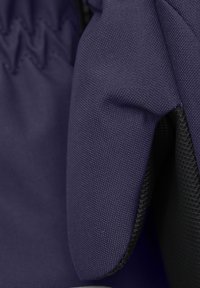 Lila tyg med en texturerad yta och svarta mesh-accenter. Designen har en vadderad yta och synliga sömmar.