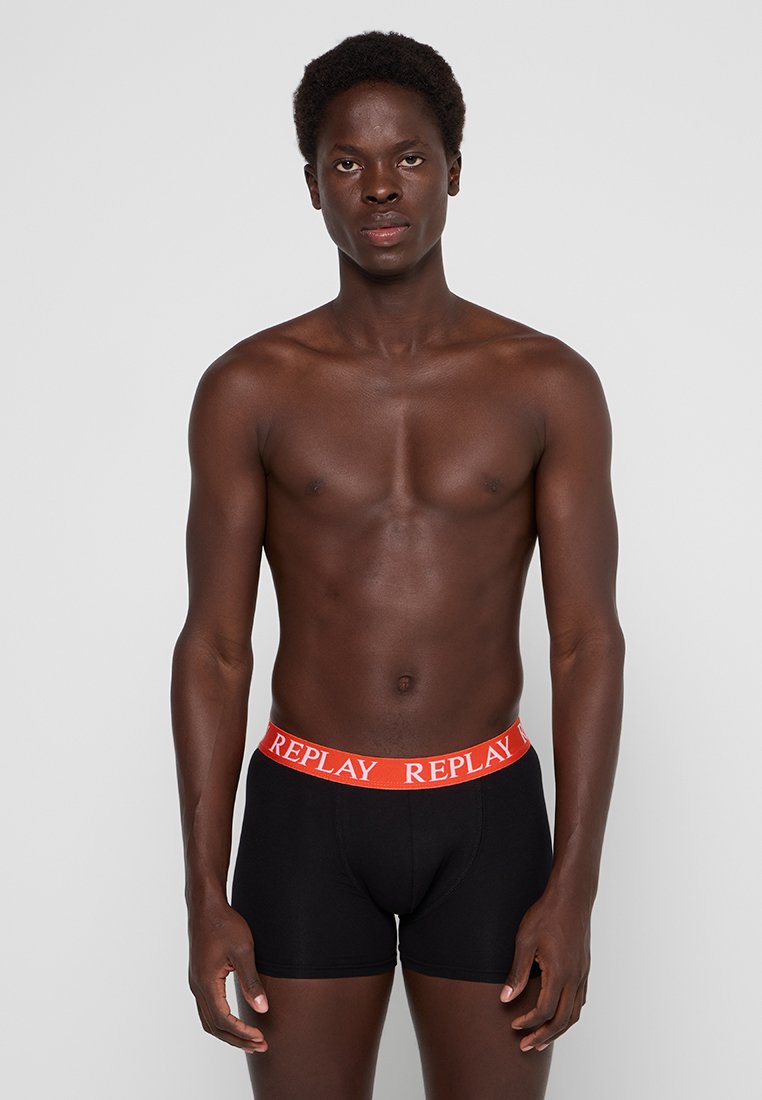 Boxer shorts noirs avec une ceinture rouge audacieuse portant le mot "REPLAY" en blanc. Texture lisse, design ajusté, sans motifs ni accents.