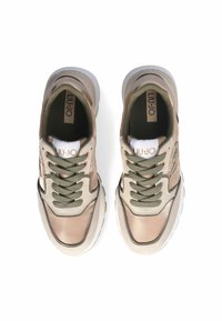 Baskets beige clair avec des lacets vert olive, en matériau lisse et brillant, avec une languette rembourrée et une semelle en caoutchouc blanc. Logo visible.