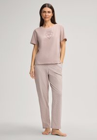Lichtroze pyjamaset met een T-shirt met korte mouwen en een eenvoudig ontwerp, en een patroon op de broek. Zacht materiaal met een relaxte pasvorm.