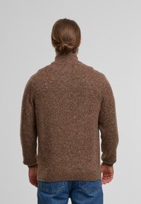 Brauner Strickpullover mit hohem Kragen, aus strukturiertem Garn. Leicht lockere Passform, mit einem dezenten Sprenkelmuster.