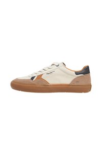 Zapatilla con parte superior de lona color crema, detalles en ante y cuero marrón, suela de goma y cordones blancos; presenta un logo y costuras decorativas.