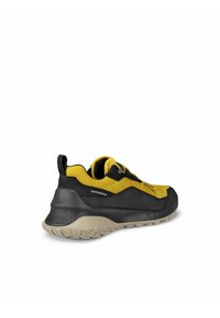 Vattentäta vandringsskor har en överdel i svart och gult textil, en texturerad gummisula och en rundad form med förstärkta detaljer.