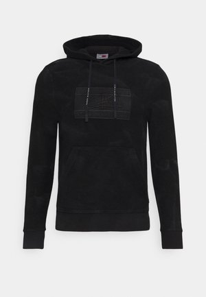 Černá mikina s kapucí a přední kapsou, šňůrky s natištěným nápisem „Tommy Hilfiger“ a jemná našitá obdélníková logo nášivka na hrudi.