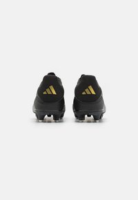 Scarpe da calcio nere con una parte superiore testurizzata, caratterizzate da strisce dorate Adidas sul tallone e una suola moldata con tacchetti visibili.