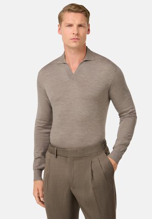 Braunes Langarm-Polohemd mit einem V-Ausschnitt-Design, aus einem glatten Material gefertigt. Das Hemd wird mit maßgeschneiderten, gefalteten dunkelbraunen Hosen kombiniert.