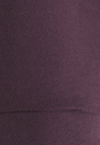 Tessuto a maglia viola con una consistenza liscia e una leggera elasticità. Presenta un dettaglio di cucitura che attraversa orizzontalmente il mezzo.